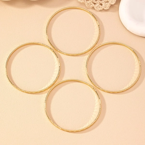 Detail of four gold bangles with diamond textures on a minimalist elegant background