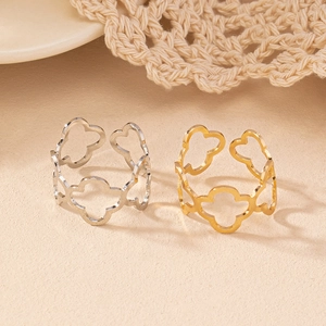 Detailed view of hollow floral open rings in gold and silver finishes on a textured background