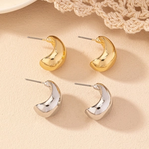 Polished gold and silver bean stud earrings set on a warm textured lace background