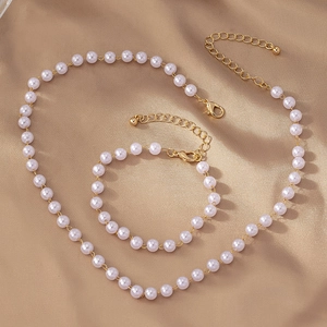 Détail d'un ensemble élégant collier et bracelet en perles blanches avec fermoirs dorés