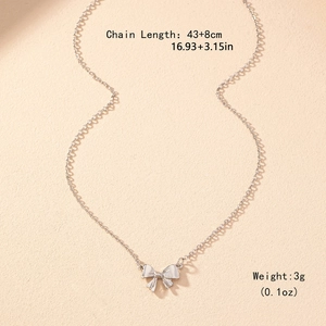 Élégant collier papillon argenté avec chaîne à vagues fines sur fond texturé beige