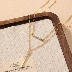 Collier double couche doré minimaliste avec pendentifs géométriques et cristaux brillants
