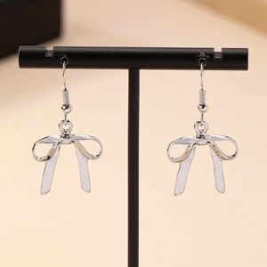 Boucles d'oreilles nœud en métal poli argenté sur un support à bijoux noir