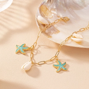 Close-up of golden starfish and white shell charms on a beach-style chain bracelet