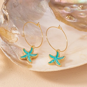 Créoles dorées avec pendentifs étoile de mer turquoise dans un coquillage nacré