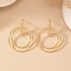 Detail of gold geometric earrings featuring double hoop nested circles and bar studs
