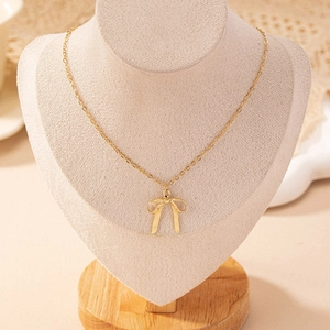 Collier élégant avec pendentif nœud doré sur un support minimaliste au style chic