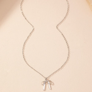 Vue rapprochée d'un collier pendentif nœud argenté avec chaîne fine sur fond texturé