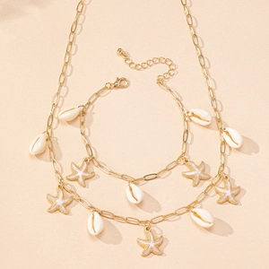 Détail de la parure collier et bracelet dorée avec pendentifs coquillages et étoiles de mer