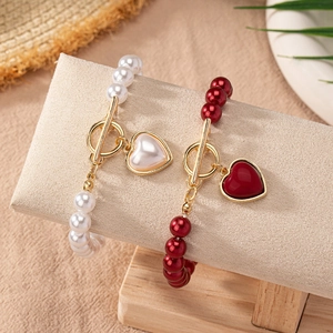 Bracelets en perles avec fermoir à bascule doré et pendentifs en forme de cœur blanc et rouge
