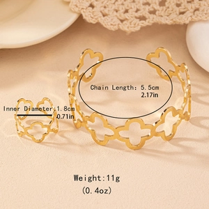 Golden cutout clover flower jewelry set with open bangle and matching ring on stone background