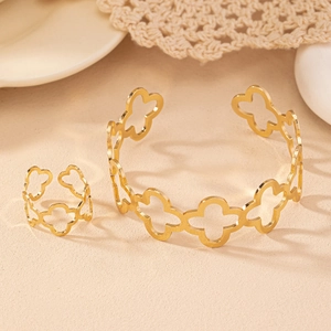 Detail view of gold floral cutout bangle and ring set on an elegant textured background