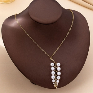 Elegant gold necklace with white pearl leaf pendant displayed on a dark brown bust stand