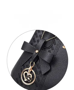 Détail d'un sac en cuir noir avec un nœud et un pendentif cœur doré à motif floral