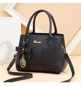 Détail du sac à main noir en cuir litchi avec logo doré et pendentif en forme de cœur