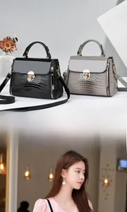 Detailed view of lizard pattern texture and gold C-buckle on a crossbody handbag