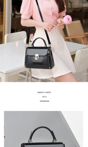 Close-up of black lizard pattern texture and gold metal turn-lock on crossbody bag