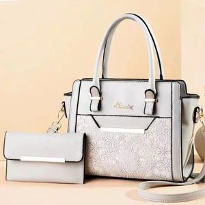 Detail of grey shoulder bag with white lace floral texture and gold hardware accents