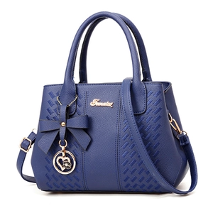 Sac à main bleu foncé en cuir avec nœud papillon et pendentif cœur en vue de trois-quarts