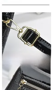 Close-up of gold metal buckles and zipper on black lizard pattern crossbody bag