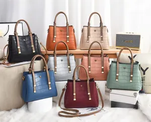 Detail showing various colors of crocodile textured tote bags with golden hardware accents
