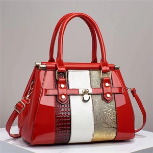Red patent leather tote with lizard texture and gold accents on a white platform