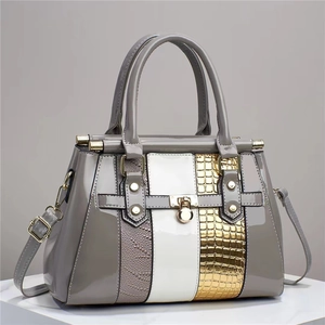 Close-up of lizard embossed leather panels and gold twist lock on tote bag