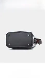 Détail de la base du sac seau en cuir noir montrant les quatre pieds de protection en métal