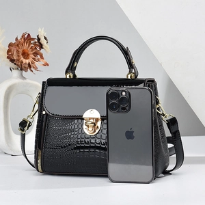Black lizard pattern shoulder bag with gold hardware and phone for scale reference