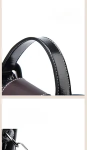 Détail du sac seau bicolore avec surpiqûres blanches et ferrures en métal doré poli