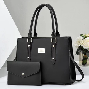 Detail view of black faux leather tote set including handbag and matching clutch bag
