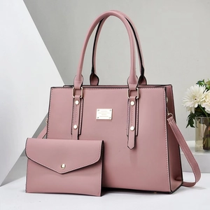 Close-up of pink PU leather tote bag set including a clutch and gold metal hardware
