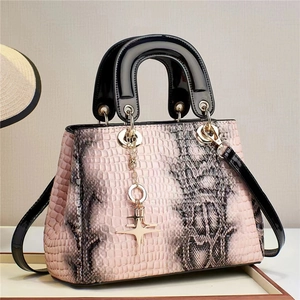 Detail of pink and gray snake texture handbag with golden star pendant and black patent leather