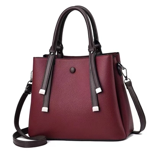 Close-up of wine red lychee grain leather handbag with dark brown handles and silver hardware