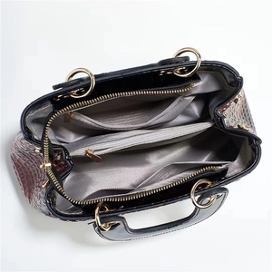 Top view detail of the bag's three-compartment interior with silver herringbone lining