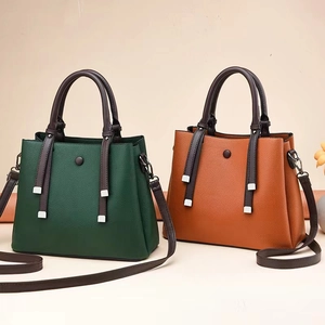 Detail of lychee textured leather handbags in forest green and caramel brown with metal hardware
