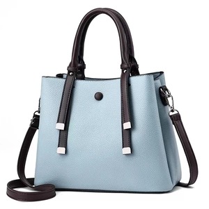 Detail of light blue lychee pattern leather handbag with dark brown contrast handles