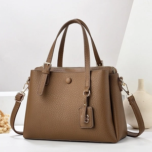 Detail of dark brown lychee texture leather handbag with gold metal B logo pendant