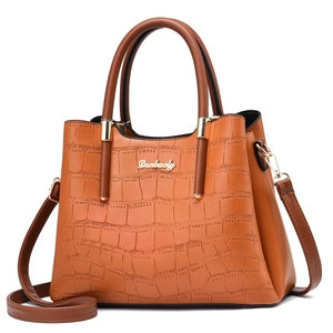 Detailed view of crocodile embossed leather texture and gold logo on brown tote bag