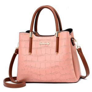 Detailed view of pink crocodile-embossed leather and golden logo on fashion handbag