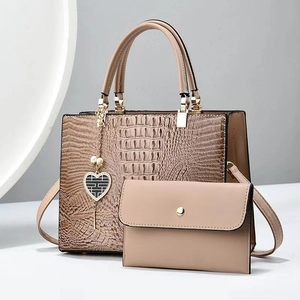 Detail of crocodile embossed leather tote with golden heart pendant and matching small pouch