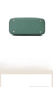 Detailed base view of dark green handbag showing four golden metal protective feet studs