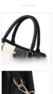 Detail of color-block tote bag featuring black handle, gold hardware, and white stitching