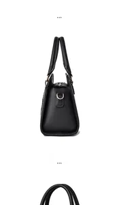 Detail view of the black leather handbag side with gold D-ring and white stitching