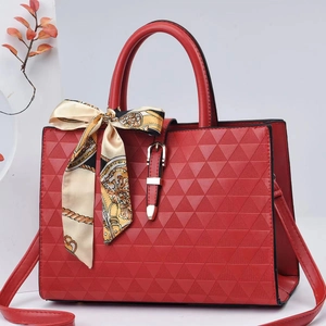 Detail der roten Handtasche mit Dreieck-Prägung und dekorativem Seidenschal-Akzent
