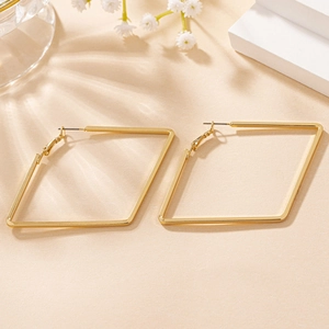 Macro shot of gold geometric rhombus earrings with high-polish finish on warm display
