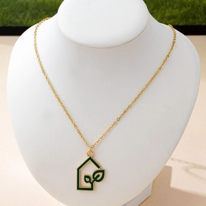 Minimalist gold house pendant necklace with green leaf pattern on a jewelry neck model