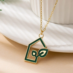 Gold house pendant necklace with green enamel leaf inlay on a delicate chain