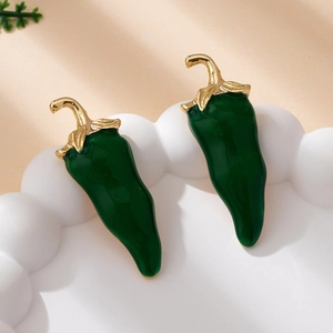 Detail of green chili pepper earrings with gold drip oil glaze on a white tray