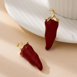 Red chili pepper drop earrings in glossy enamel with gold metal stems on a white surface